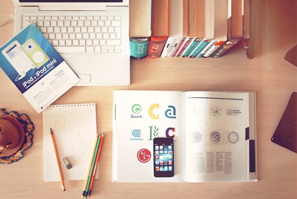 Books, a laptop and a smartphone on a desk.