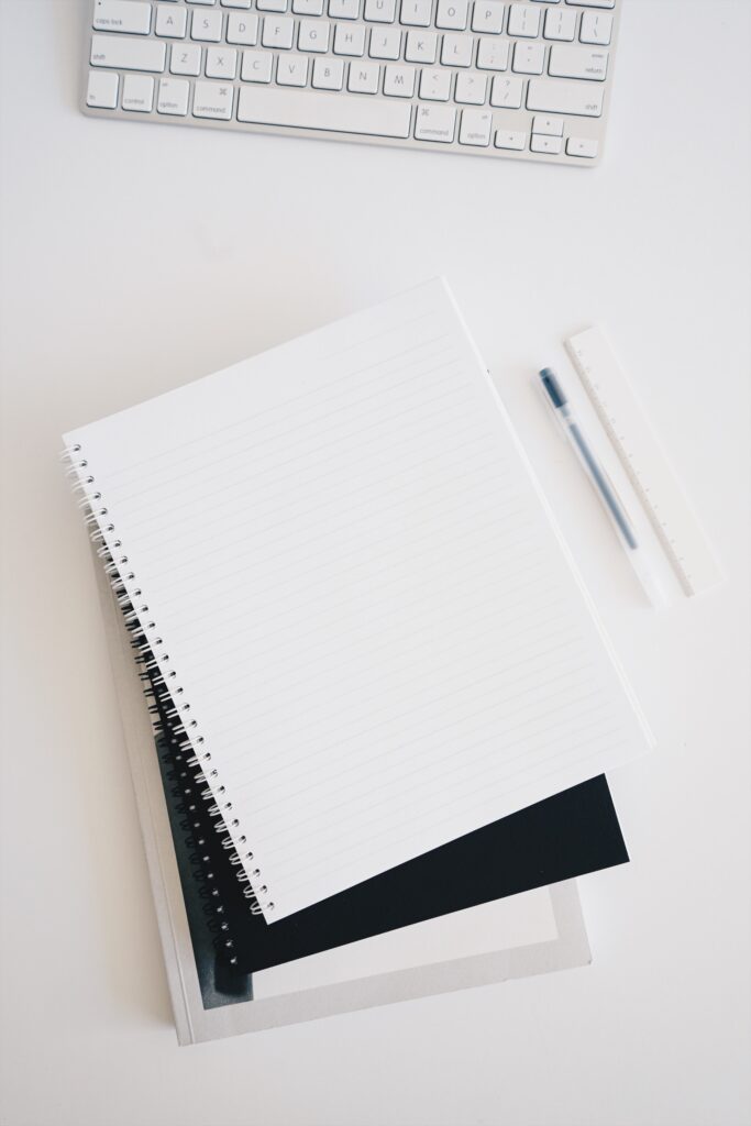 notebooks close to pens and a keyboard.