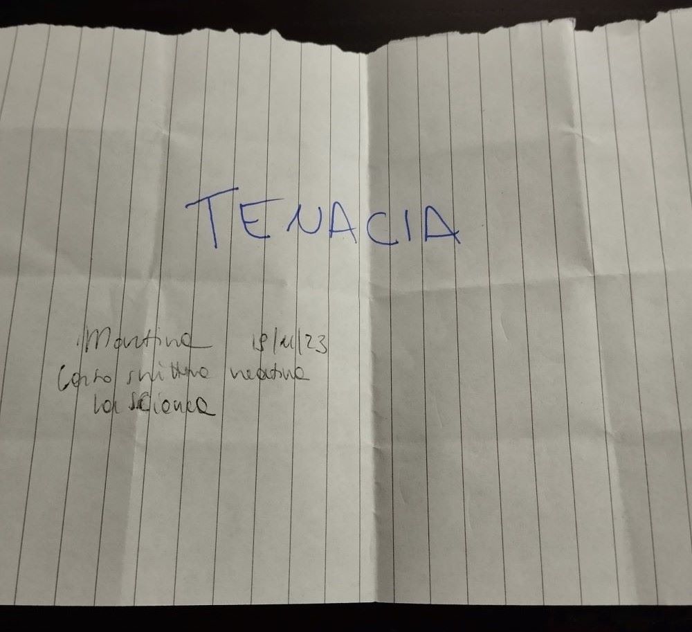 Un foglio bianco a quadretti con la scritta Tenacia in stampatello.