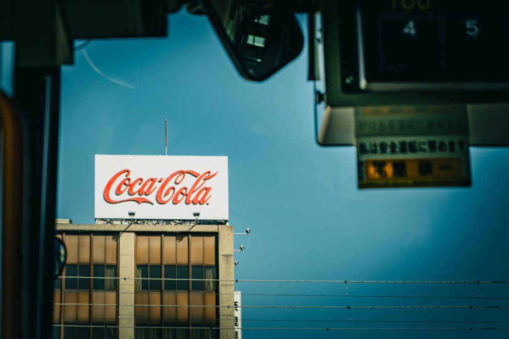 Un palazzo sullo sfondo con la scritta Coca Cola. In primo piano un semaforo.